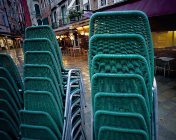 Close-up of green stacked chairs on footpath at dusk