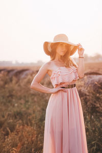 Woman wearing hat standing on field against sky