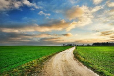 Road amidst field against sky