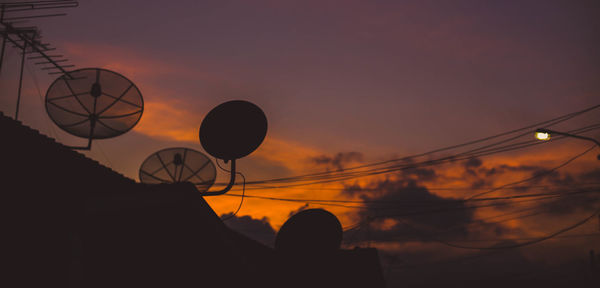 Low angle view of silhouette telephone pole against sky during sunset