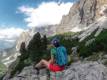 Full length of man sitting on rock against mountains