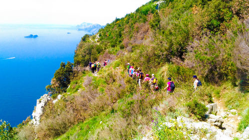 People on mountain by sea against sky