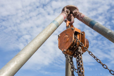 Low angle view of rusty chain against sky