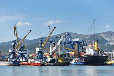 Cranes at harbor against sky