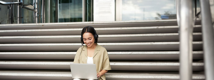 Portrait of young woman standing against building