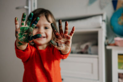 Portrait of girl showing messy hands at home