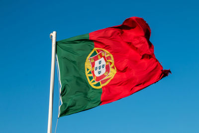 Low angle view of flag against blue sky