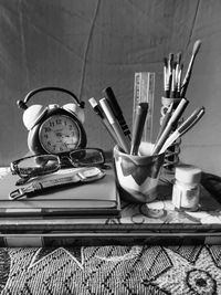 Close-up of books and pen with alarm clock on table