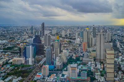 Aerial view of cityscape against cloudy sky