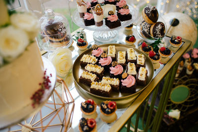 From above sweet delicious creamy chocolate cakes on round tray doughnuts and berry tartlets on festive table in dessert bar in cafe