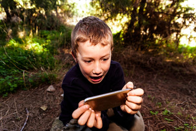 Portrait of smiling boy holding smart phone outdoors