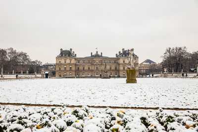 Snow covered buildings and trees against sky