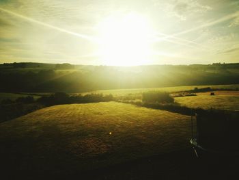 Scenic view of grassy field against sky during sunset