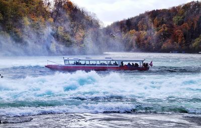 People in ferry boat on river during autumn