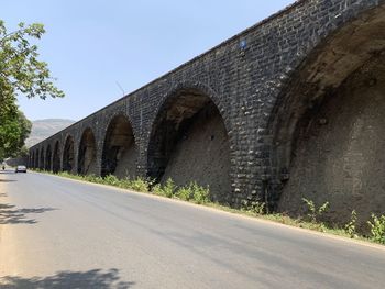 Road by built structure against clear sky