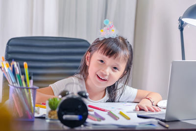 Portrait of cute girl sitting on table at home