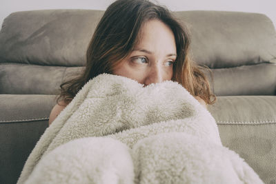 Portrait of woman lying on sofa at home