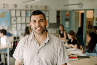 Portrait of smiling male teacher standing in classroom