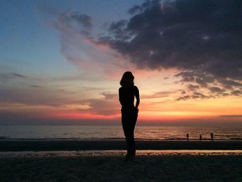 Silhouette man standing on beach against sky during sunset