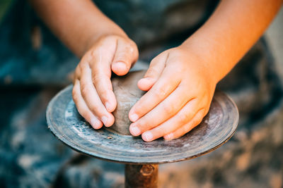 Cropped hands of potter making clay pot at pottery