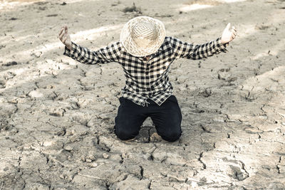 Woman kneeling on barren field