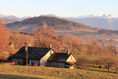 Houses by mountains against clear sky during sunset