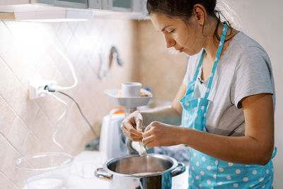 Side view of woman preparing food in kitchen