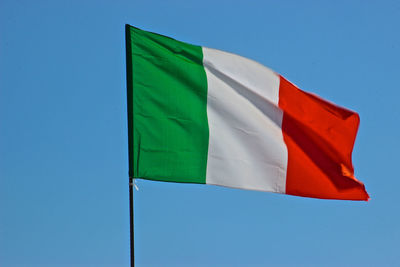 Low angle view of flag against blue sky