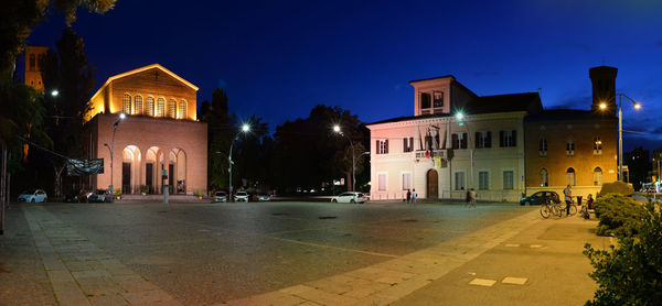 Illuminated street amidst buildings at night