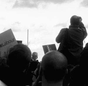 Rear view of people photographing against sky