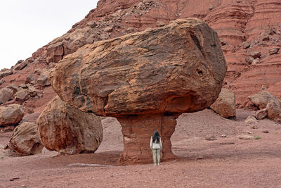 Hiker by a large balanced rock in the glen canyon national recreation area in arizona