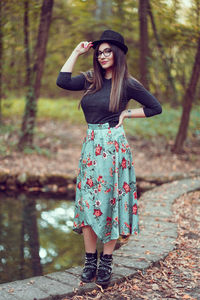 Full length of young woman standing against tree