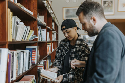 Young man discussing over book with professor in library