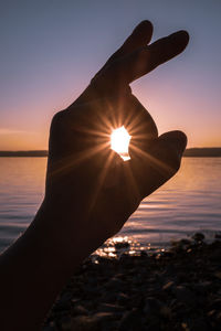 Cropped hand gesturing against sky