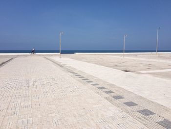 Scenic view towards the beach from an urban plaza against clear blue sky 