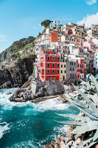 Buildings by sea against sky