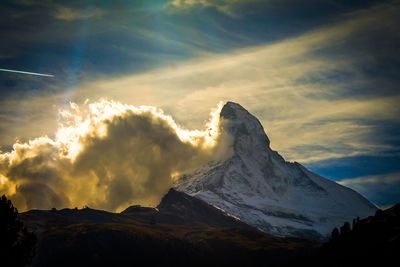 Low angle view of snowcapped mountain against cloudy sky during sunset