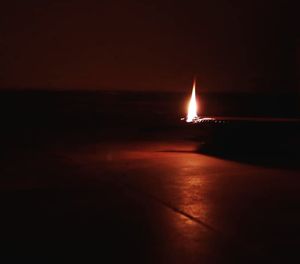 Illuminated lights on beach against sky at night