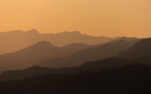 Scenic view of silhouette mountains against orange sky