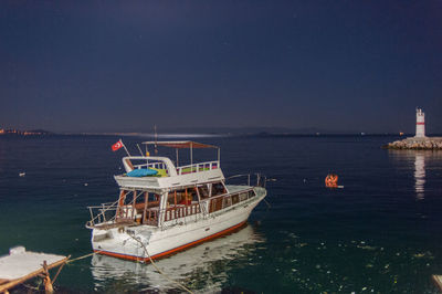 Boat moored on sea against clear sky at night