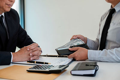 Midsection of man holding smart phone on table