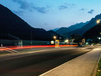 Light trails on road against sky at night