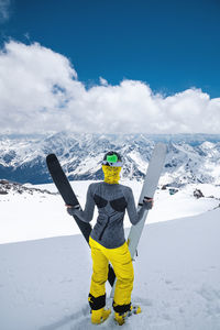 Rear view of person on snowcapped mountain against sky