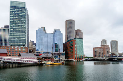 Modern buildings by river against sky in city