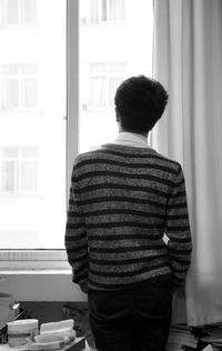 Rear view of a man standing against window