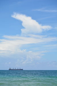 Scenic view of sea against sky with freight ship and cloud