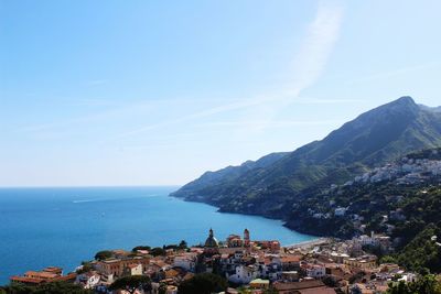 Aerial view of town by sea and mountains against sky