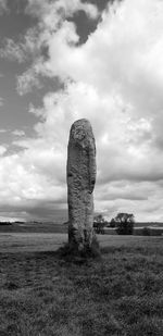 Stone structure on field against cloudy sky