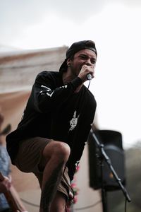 Musician singing while standing against sky