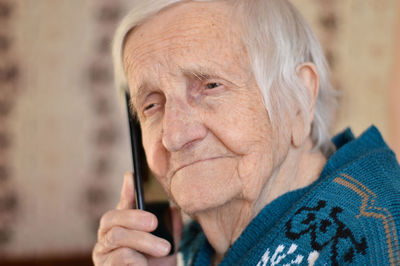 Close-up of a 90-year-old elderly retired woman who is talking smiling on the phone. selective focus